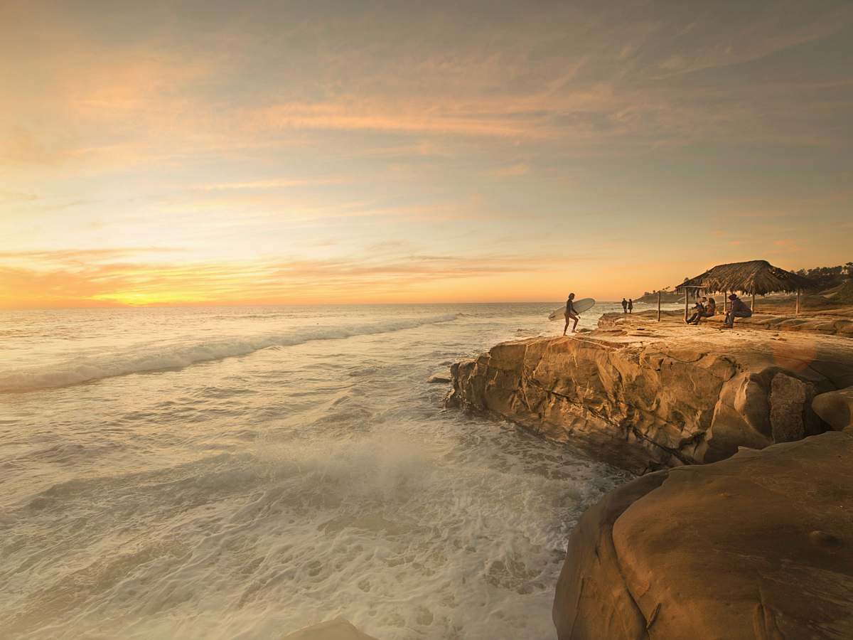 san diego person holding surfboard near body of water beach wallpapers